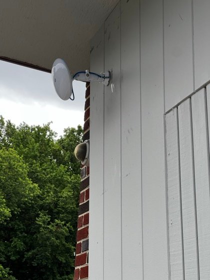 A point-to-point wireless dish on an articulating mount, with a dome camera on the corner below.